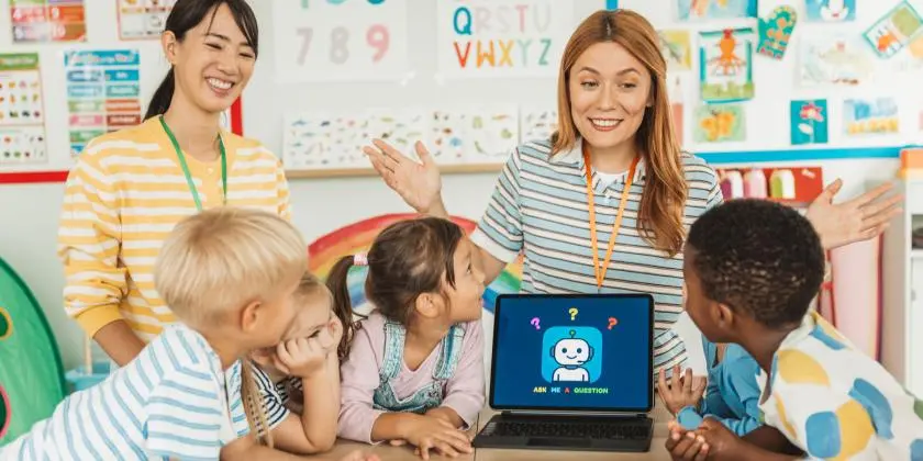 A classroom with adults and children gathered around a computer