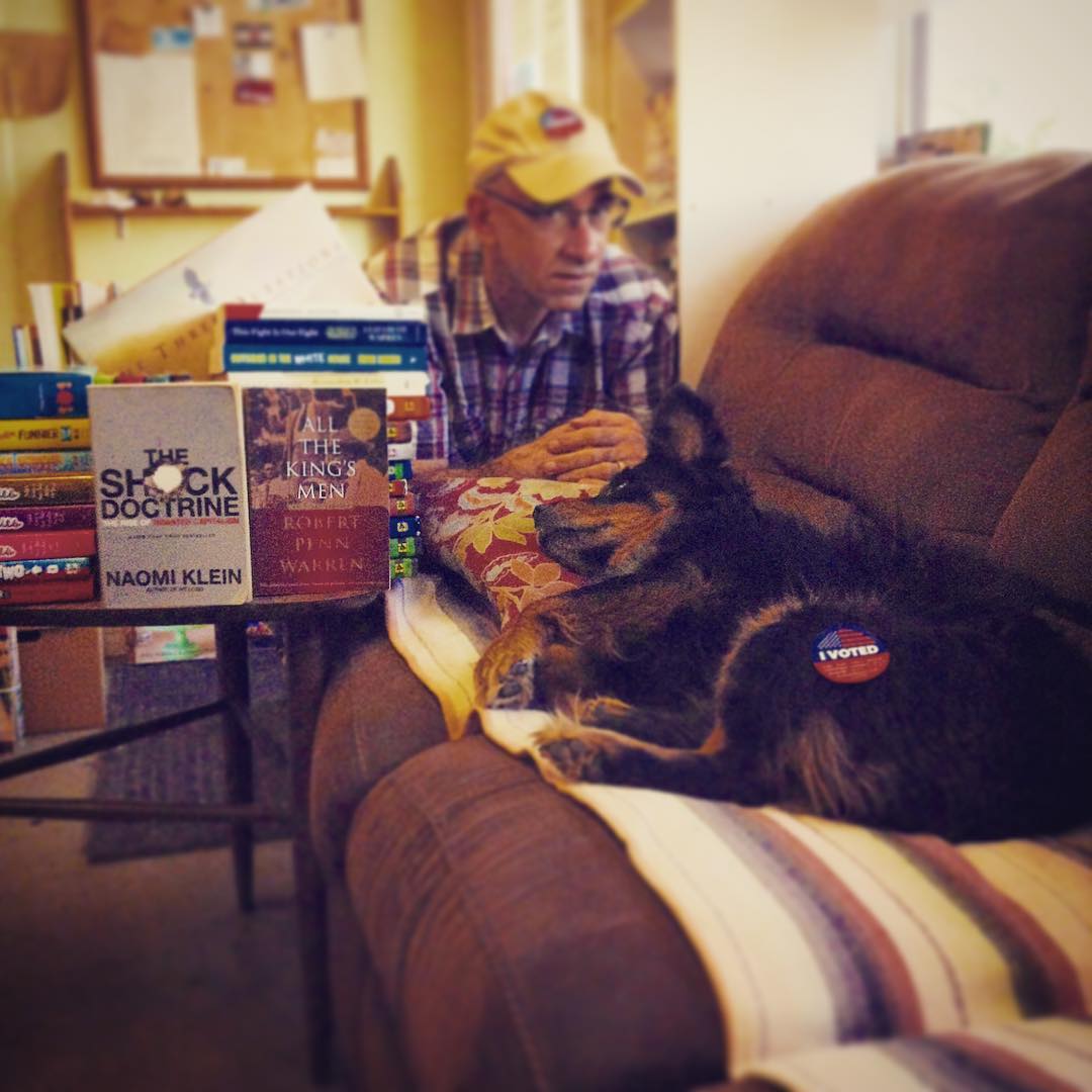Jeremy Kaplan, owner of READ Books poses with Florence, shop dog inside of READ Books couch