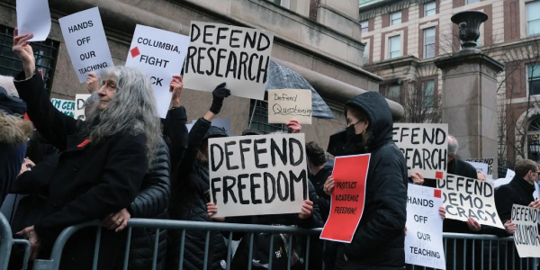A group of protesters hold signs that advocate for defending freedom.
