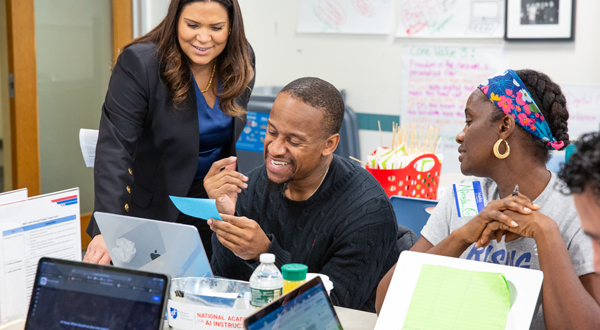 Three African American teachers sit together on a table.