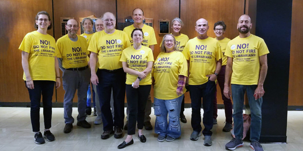 A group of union workers wearing yellow shirts stand together. 