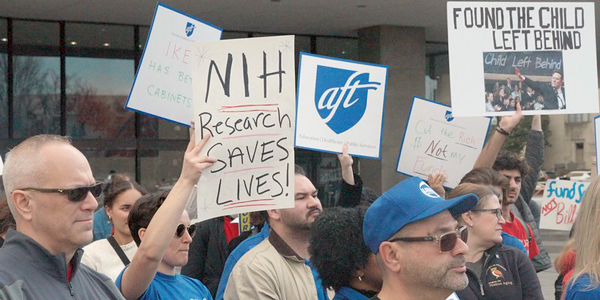 A group of protestors hold up signs to save scientific research.