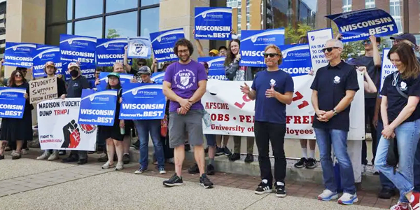 A group of protestors stand together holding signs. 
