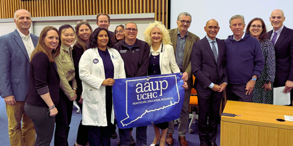 A group of professionals stand together holding a banner.