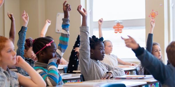 A class of students raising their hands. 