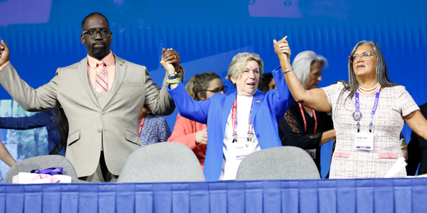 Re-elected officers Fedrick Ingram, Randi Weingarten and Evelyn DeJesus hold hands onstage. Re-elected officers Fedrick Ingram, Randi Weingarten and Evelyn DeJesus hold hands onstage.