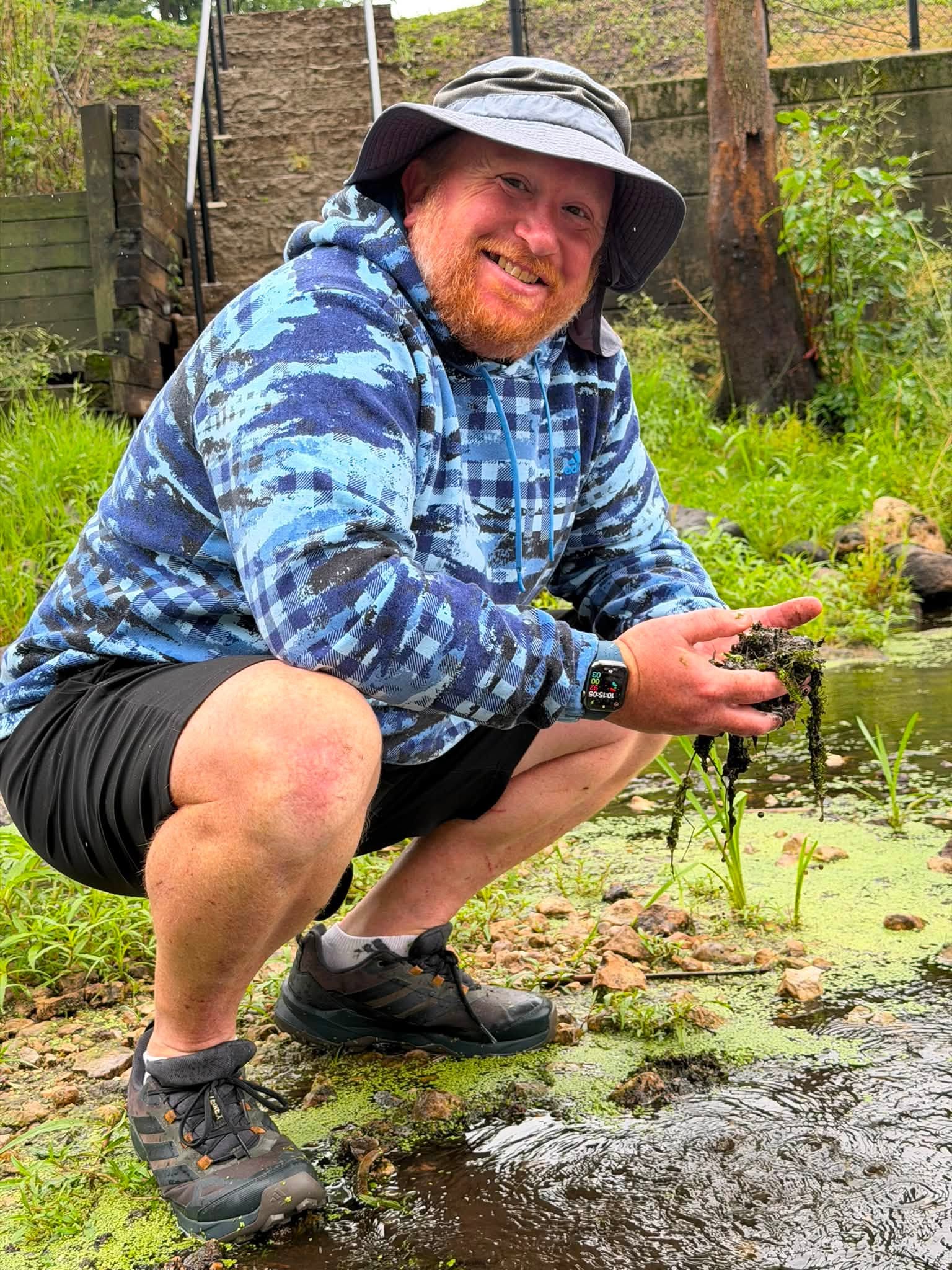 Christian holding a handfull of invasive milfoil from the river.