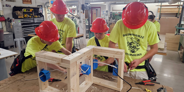 A group of teens wearing hard hats build a project together. A group of teens wearing hard hats build a project together.