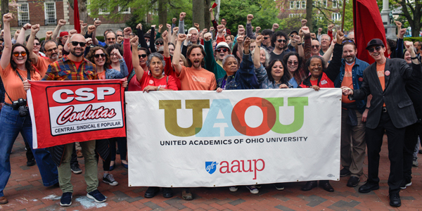 A group of people stand holding up a banner.